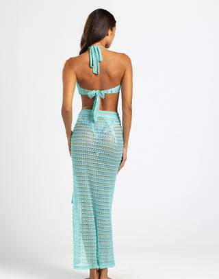 The model is wearing an aqua bandeau-style top with a halter tie and a keyhole cutout at the center, combining a chic and beach-ready design.